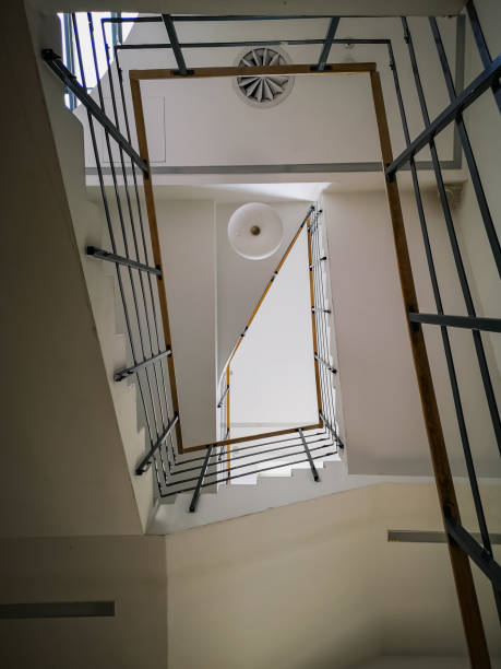 istock Looking up to Rectangular staircase with light wooden handrail and white ceiling 1426971901