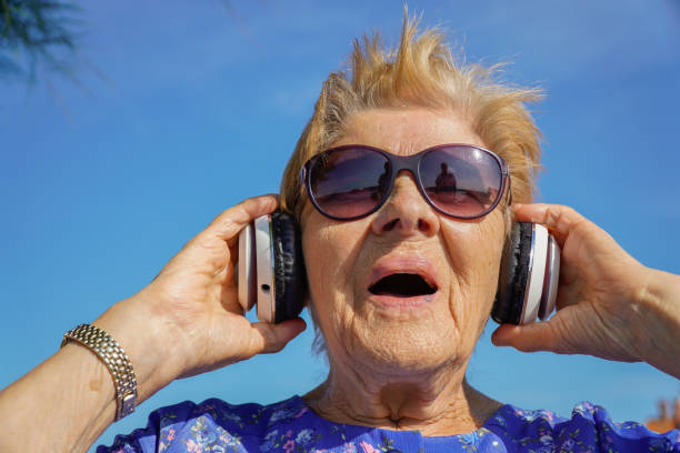 istock old woman listen music with headphone. Neuronal development 1426972646
