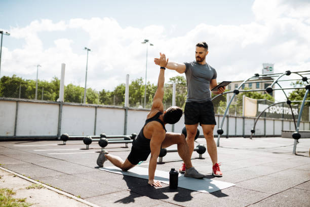 istock Fitness instructor and Latin trainee on outdoor training, man is stretching and coach is helping him 1426974488