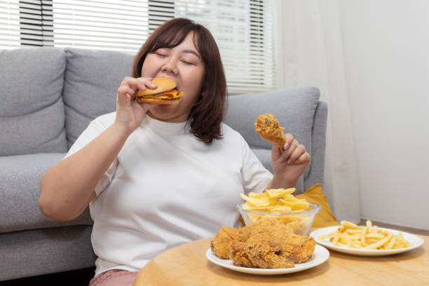 istock Overweight Woman Enjoy Eating Beef Burger with Fried Drumstick Chicken 1426976887