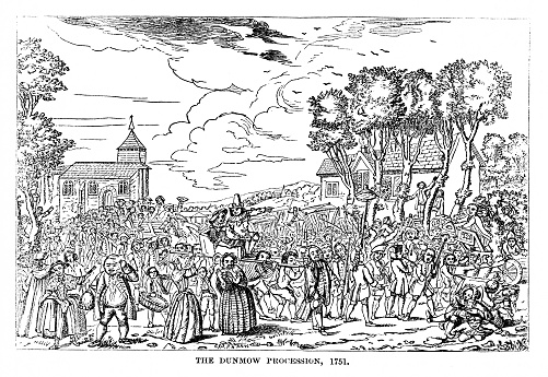 The Dunmow Flitch: a procession of people follow the winning married couple who are being carried in a chair on the shoulders of four men while others walk in front carrying a piece of bacon on a stick. The old English custom is that any couple who can say they have been happily married for one year and one day are entitled to a free piece of bacon.  Original engraving by C. Mosley in the London Times, 1751. Illustration in my personal archives published in 1863. Copyright has expired and is in Public Domain.