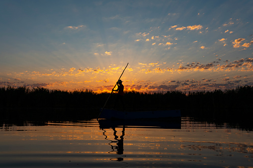 Senior son and elderly father enjoying fishing on a pontoon boat tour on a lake in summer. They are family, senior dad is in his eighty, son in his fifties. They are wearing casual clothes. Horizontal outdoors full length shot with copy space. This as taken in the Laurentides, Quebec, Canada.