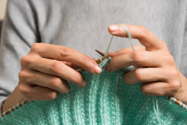 feche acima das mãos femininas segurando agulhas de tricô de bambu e tricotando suéter de lã verde. hobby, relaxamento, saúde mental, estilo de vida sustentável - tricotar - fotografias e filmes do acervo