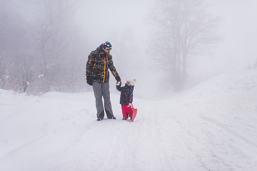Single father and daughter on top of the mountain, enjoying winter snow.