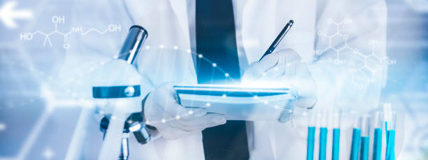 istock biochemical research scientist working with a microscope for the virus,Doctor man write a history of the experimental results in a , laboratory glassware containing chemical liquid for design. 1426988554