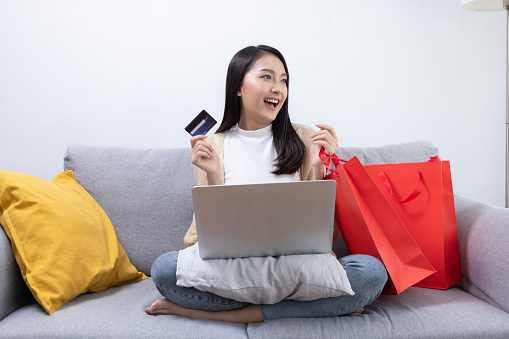 Asian Woman Holding Credit Card in Front of Her Laptop For Onlie Shopping
