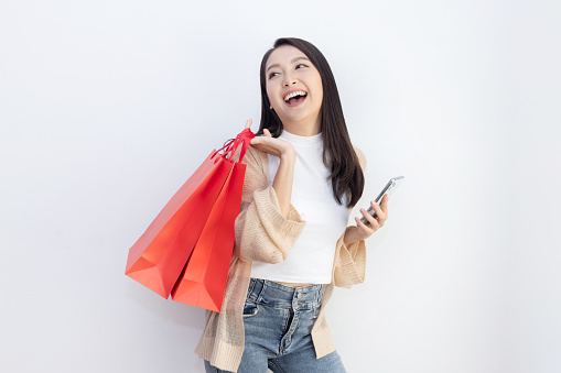 Isolated Happy Asian Woman Holding Shopping Bag with Mobilephone in Her Hand