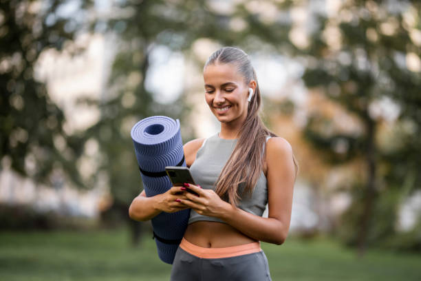 istock Sporty woman using smart phone and holding exercise mat 1427003055