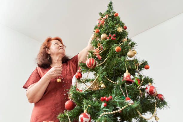 크리스마스 트리를 장식하는 라틴어 성숙한 여성. 낮은 각도보기, 복사 공간 - artificial tree 뉴스 사진 이미지