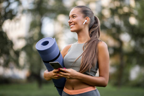 istock Sporty woman using smart phone and holding exercise mat 1427006505
