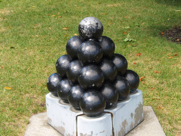 istock Stack Of Black Round Cannon Balls On Cement Platform Green Grass 1427008772