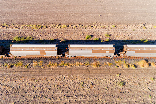 Freight train cycterns at grain salo storage warehouse in Moree rural town of Australian artesian basin - aerial top down view.