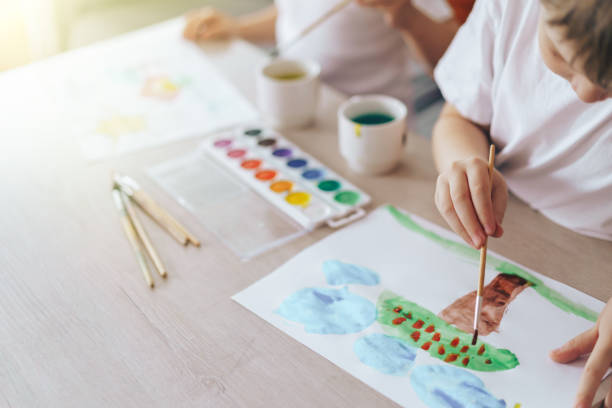 istock Children paint green grass with a tree and blue clouds 1427038968
