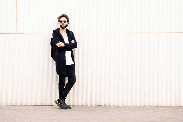 istock young man with sunglasses leaning in a white wall 1427040792
