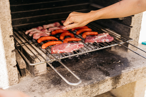 hands of young latin woman rubbing salt on meat at a barbecue. Food