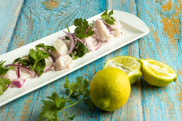 rectangular plate with fish ceviche with red onion and cilantro. Fresh lemons accompany the dish on blue worn table rectangular plate with fish ceviche with red onion and cilantro. Fresh lemons accompany the dish on blue worn table fresh cilantro stock pictures, royalty-free photos & images