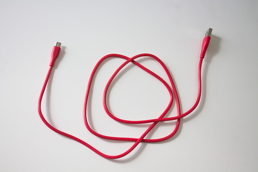 Red usb charging cable placed on a white background