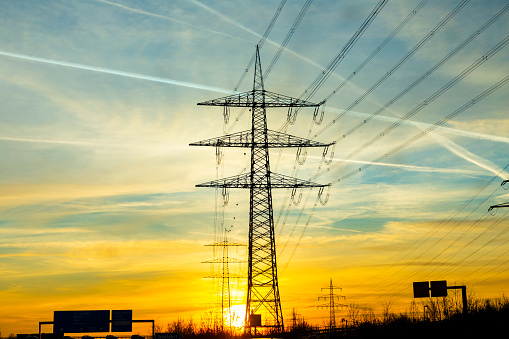 scenic sunset seen from highway with electric pylon and condensation stripes from aircrafts at the sky