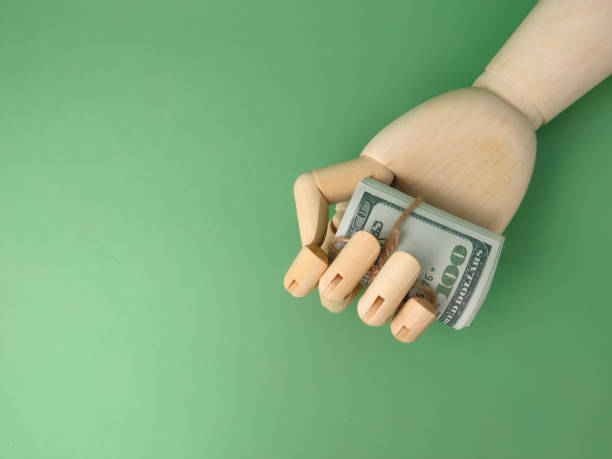 istock Wooden hand holding banknotes on a green background with copy 1427076918