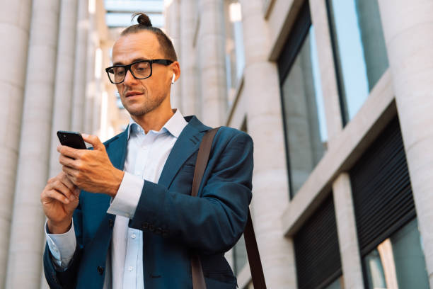 istock Young handsome businessman using smartphone at the city. 1427092924