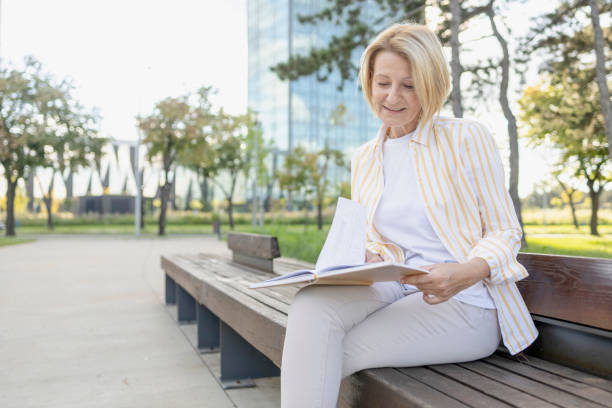 istock Beautiful woman reading a book on a park bench 1427107001