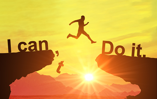 Silhouette man jumping over cliffs for I can do it , good mindset by never give up concept. Motivational image, nothing is impossible. I can do it concept. Business, success, achievement concept.