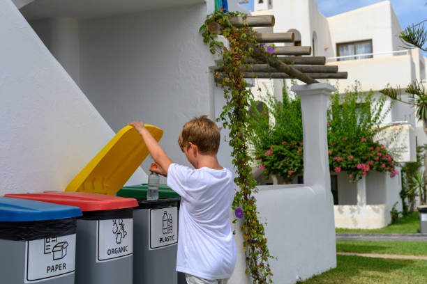 istock Boy throws a plastic bottle into the yellow container for recycling. 1427116679