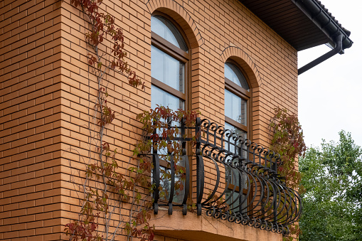 view of the facade of the building in the city, red brick house balcony with long windows, autumn decoration of the wall, modern architecture