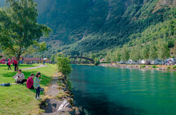 die menschen genießen einen sonnigen tag am fluss flam in flåm. sommerzeit in norwegen. - sogn og fjordane county stock-fotos und bilder