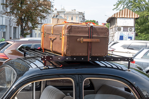 old vintage suitcases on top of the car, concept of travelling by car, road trip, moving to different place, adventure