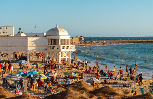 Bathers on the beach of La Caleta in the summer sunset of the city of Cadiz. Andalusia