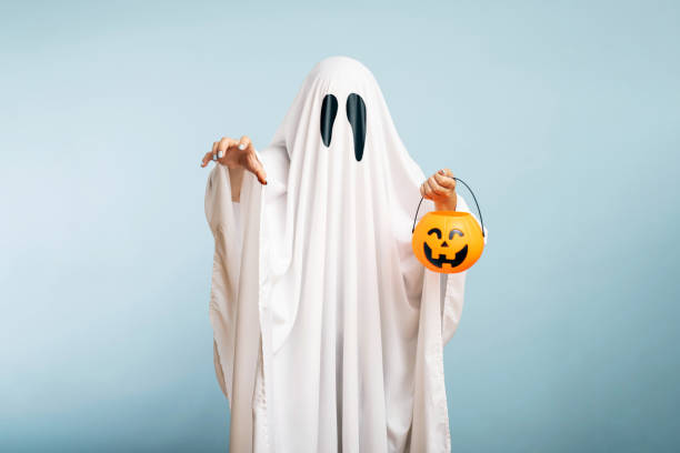 một con ma trắng với đôi mắt đen, được làm từ ga trải giường với giỏ bí ngô - trang phục người làm hình ảnh sẵn có, bức ảnh & hình ảnh trả phí bản quyền một lần