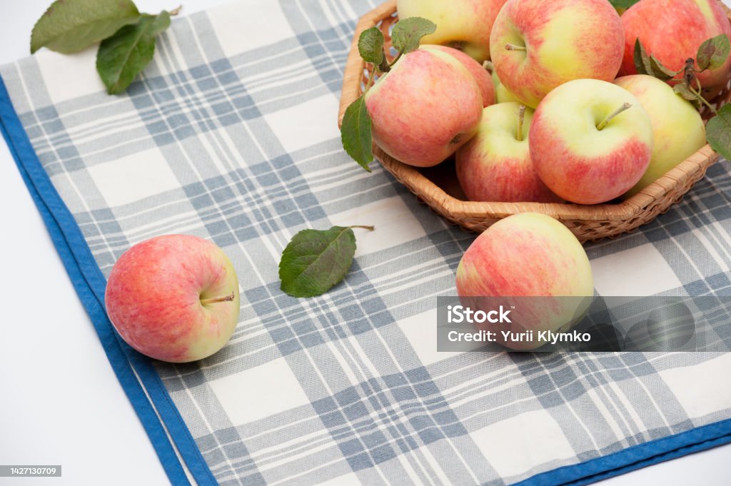 Juicy apple fruits Juicy ripe apples in the wicker plate on a table with a checkered tablecloth Apple - Fruit Stock Photo