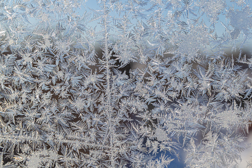 Melting ice running down a window pane, Closeup of frozen window pane surface with ice crystals