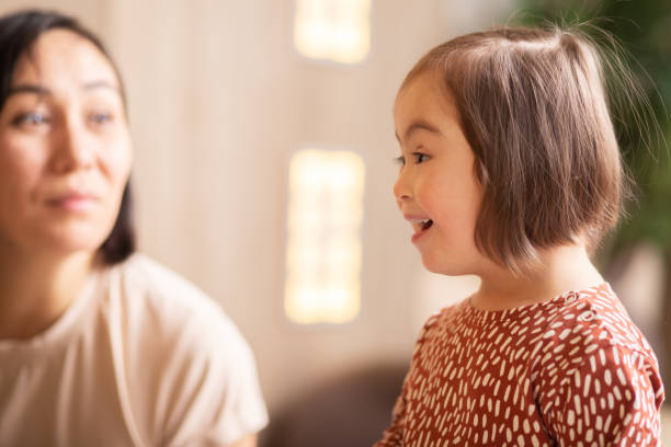 cute child with down syndrome at christmas reads poetry with mom stock photo