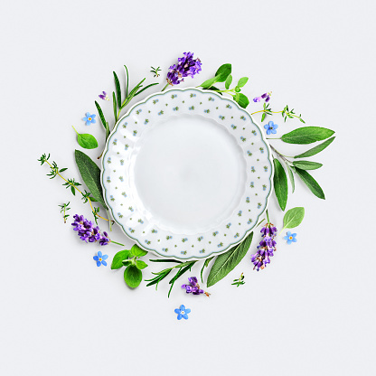 Rosemary, lavender, marjoram, sage, thyme and vintage plate creative card and layout. Frame with fresh herbs and flowers on gray background. Top view, flat lay. Copy space. Design element