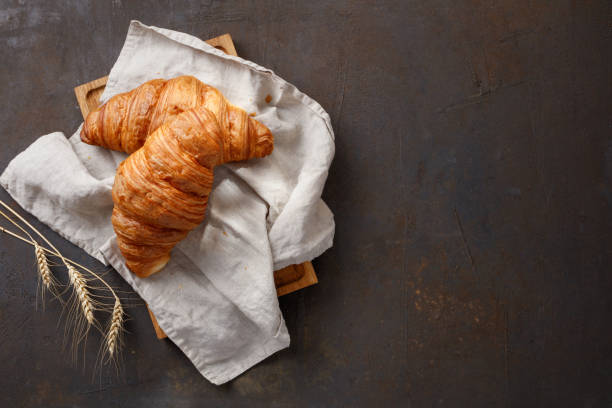 istock Board and gray napkin with tasty croissants on rusty table. 1427146339