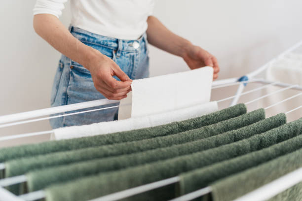 mujer colgando toallas de felpa limpias en el tendedero en el interior - towel hanging bathroom railing fotografías e imágenes de stock