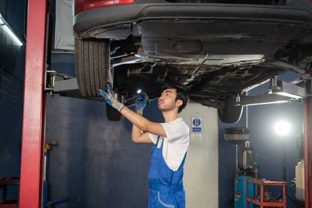 auto mechanic is walking to check the condition of the car that is on the hoist in the garage. stock photo