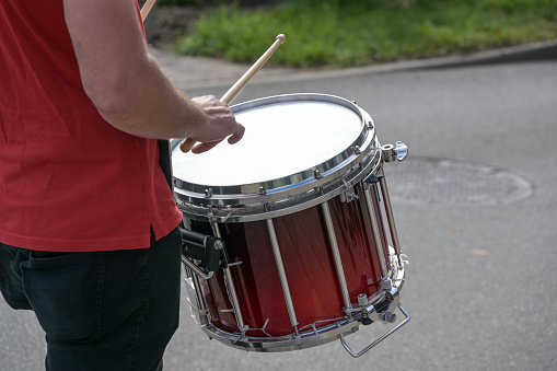 Mobile snare drum played in a marching band, musical percussion instrument for the rhythm at a parade on the street, selected focus, narrow depth of field