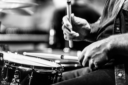 learning to play drums. hold the drumstick, sit in front of the snare drum, Black and white image (high iso shot)
