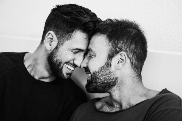 Gay men couple having tender moment together at home - Soft focus on left man eye - Black and white editing stock photo