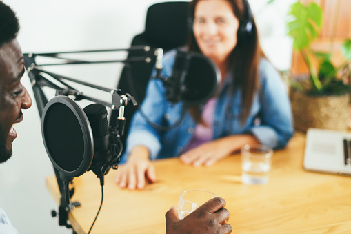 Hosts having podcast session together - African speaker making an interview during live stream - Soft focus on microphone