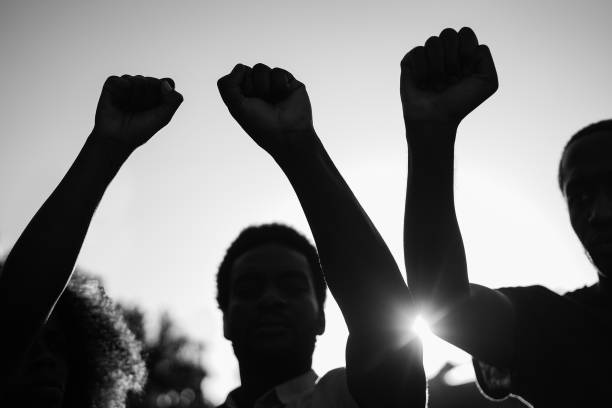 Black demonstrator people holding hands against racism - Focus on fists - Black and white editing stock photo