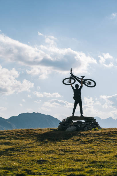 istock Man holds e-mountain bike overhead, in alpine meadow 1427213118