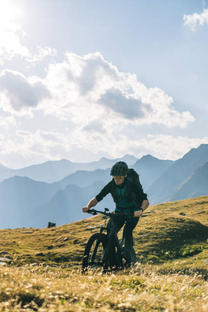 istock Scenic view of man e-mountain biking in alpine meadow 1427214065
