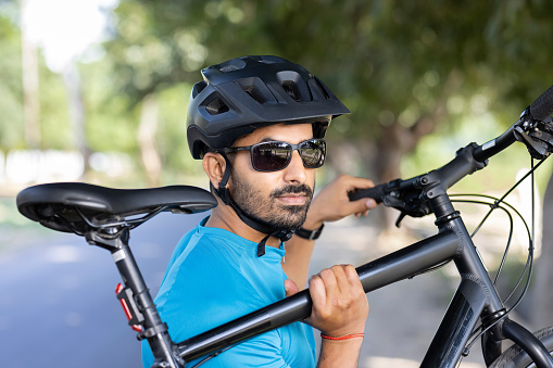 Man in sports helmet carrying mountain bike