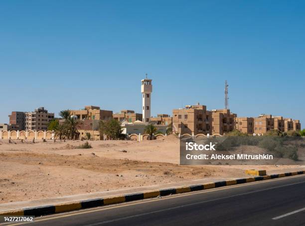View From The Road To The Low Houses Of Local Residents Surrounded By Desert And Palm Trees Against The Background Of A Blue Sky Copy Space Safaga Egypt Stock Photo - Download Image Now