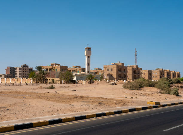 view from the road to the low houses of local residents surrounded by desert and palm trees against the background of a blue sky. copy space. safaga, egypt - safaga imagens e fotografias de stock