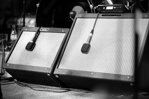 An electric bass guitar leaning against a guitar amplifier. Focus is on the knobs of the amp.  Black background.